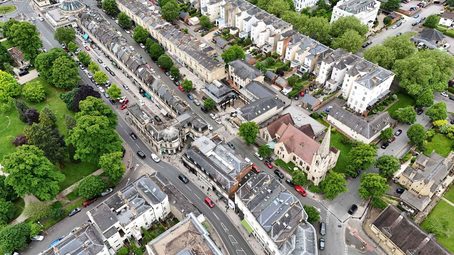 An aerial view of a town with many buildings, roads, cars, and trees