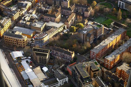 An aerial view of a dense urban area with various buildings, roads, and some green spaces